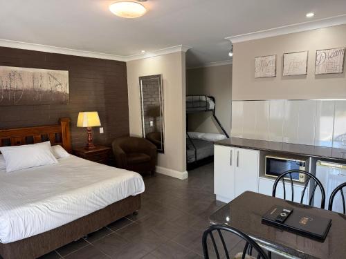 a bedroom with a bed and a table and a kitchen at Country Leisure Motor Inn in Dubbo