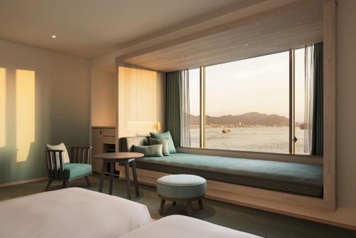 a bedroom with a window with a bed and a table at RISONARE Shimonoseki in Shimonoseki