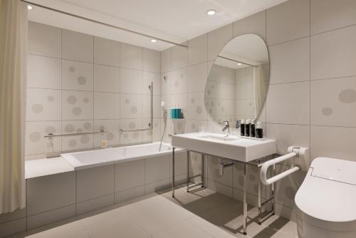 a bathroom with a sink and a tub and a mirror at RISONARE Shimonoseki in Shimonoseki