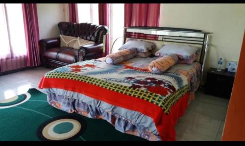 a bedroom with a large bed and a chair at Ruteng YosPrima Garden in Lao