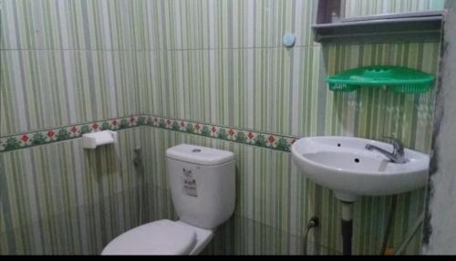 a bathroom with a toilet and a sink at Ruteng YosPrima Garden in Lao