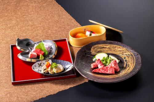 a table with plates of food and a bowl of soup at Tokiwa Hotel in Kofu