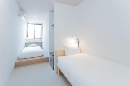 a white bedroom with a bed and a window at atic Guesthouse in Takamatsu