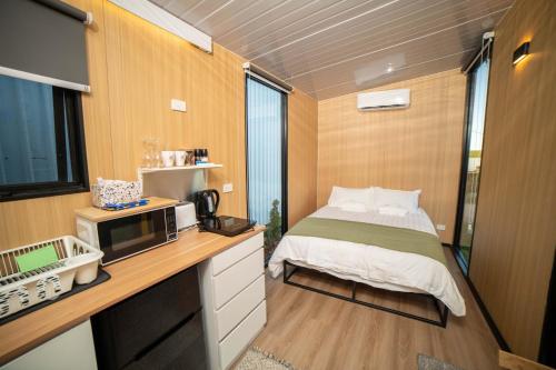 a small room with a bed and a microwave at The Orchard View by Tiny Away in Nashdale