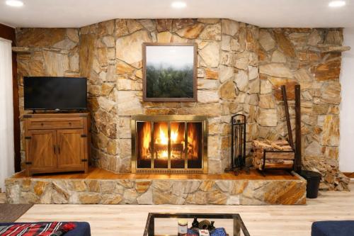 a living room with a stone wall with a fireplace at SPECTACULAR CATSKILLS VACATION OASIS- AMAZING Mountain Views-2 MINS TO HUNTER! in Hunter