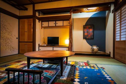 a living room with a table and a rug at Tsukasa Ryokan in Saga