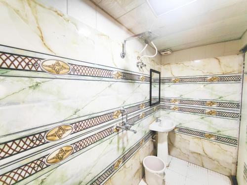 a bathroom with marble walls and a toilet at Hotel kingsman in Rudrapur