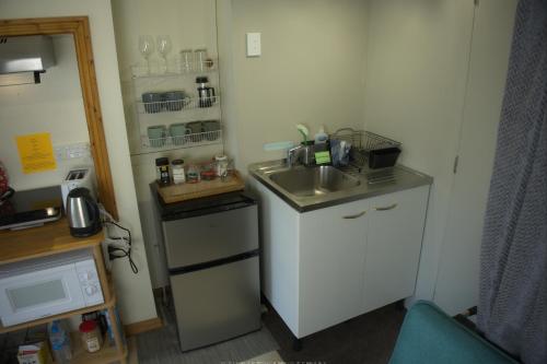a small kitchen with a sink and a microwave at Hilltop guest room, Escape the city! in Pukehiki