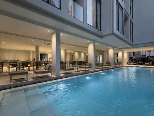 a swimming pool in a building with tables and chairs at POR Kotchasarn in Chiang Mai