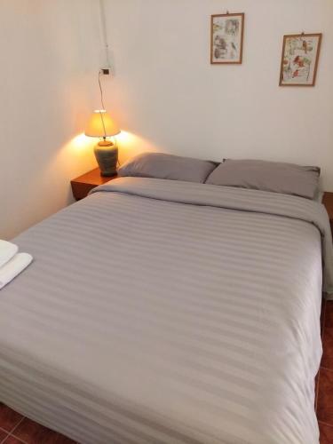 a bedroom with a large white bed with a lamp at Mountain View Garden House in Ban Chong Phli