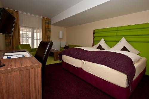 una camera con un grande letto con testiera verde di Am Schlosspark a Worms