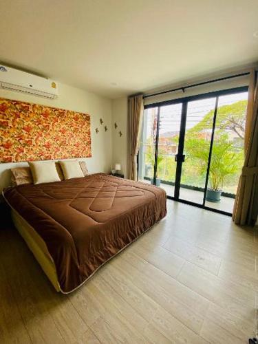 a bedroom with a large bed and a large window at Bann Chidtha family suite full kitchen near Suvarnabhumi Airport in Bangkok