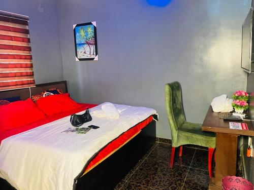 a bedroom with a bed with a desk and a chair at JEVENOM HOTEL in Ibafo