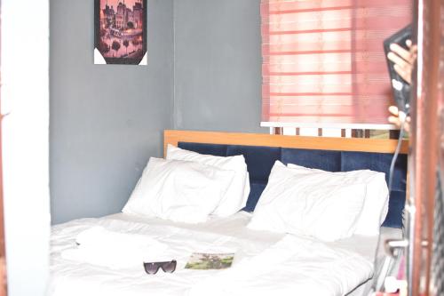 a bed with white pillows and a headboard with glasses on it at JEVENOM HOTEL in Ibafo