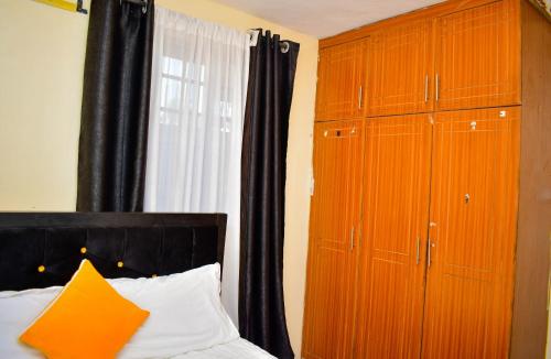 a bedroom with a large wooden cabinet next to a bed at Cozy Homes in Thika