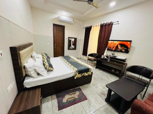 a bedroom with a bed and a tv and a chair at Raghav inn in Karnal
