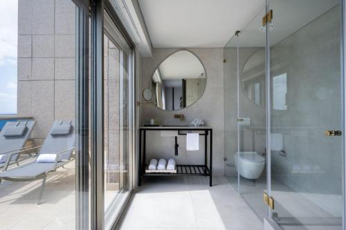 een badkamer met douche, wastafel en spiegel bij Leonardo Plaza Haifa in Haifa