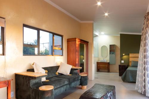 a living room with a black couch and a bed at Fourfields Hogsback in Hogsback