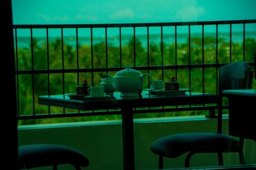 a table with a teapot and cups on a balcony at Sasha Transit Hotel in Katunayake