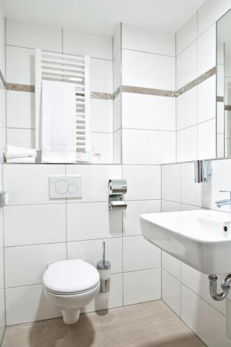 a white bathroom with a toilet and a sink at Fair Hotel Europaallee in Frankfurt
