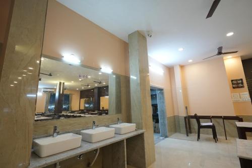 a bathroom with three sinks and a large mirror at Hotel SagarPriya in Digha