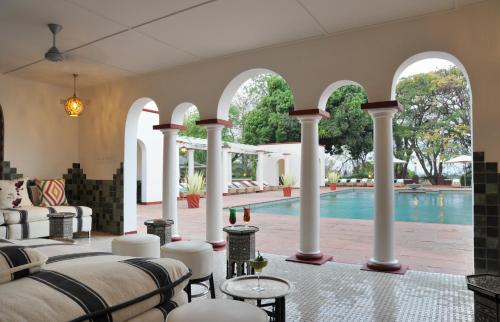 uma villa com piscina e colunas brancas em The Victoria Falls Hotel em Victoria Falls