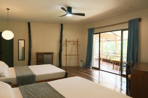 a bedroom with two beds and a ceiling fan at Easy Does It Guesthouse Siargao in General Luna