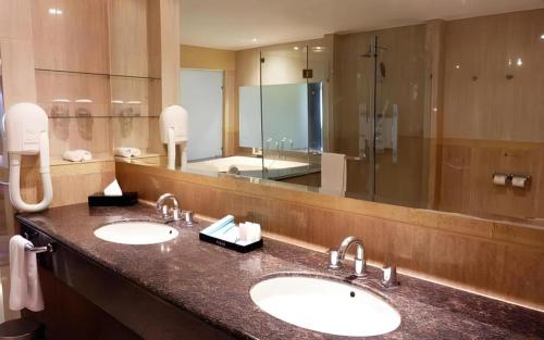 un bagno con due lavandini e un grande specchio di Grage Hotel Cirebon a Cirebon