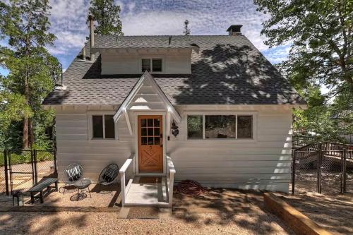 a small white house with a door and a porch at Yama Cabin - 5 min walk to the village, EV plug, hot tub, kid & pet friendly in Lake Arrowhead