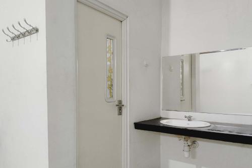 a white bathroom with a sink and a mirror at RedDoorz at Trans Hotel Cilegon in Toyamarta