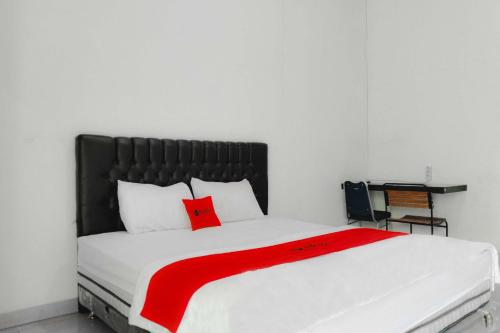 a bedroom with a large white bed with red pillows at RedDoorz at Trans Hotel Cilegon in Toyamarta