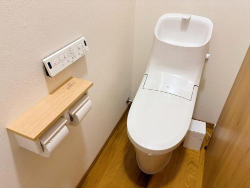a white toilet in a bathroom with a wooden floor at Casa Arita in Zōshuku