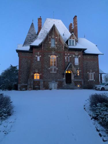 een groot bakstenen huis met sneeuw op de grond bij Le Manoir des Rochers in Bouère