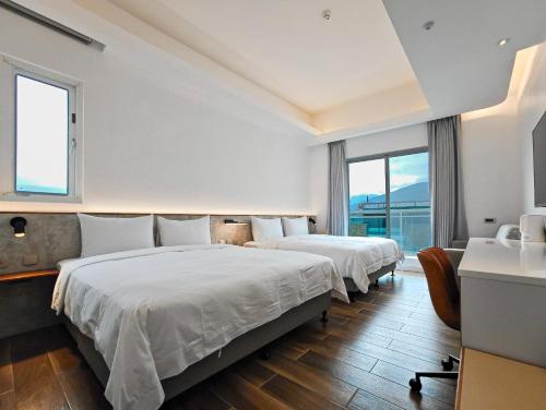 two beds in a hotel room with windows at Hanpin Homestay in Yuli