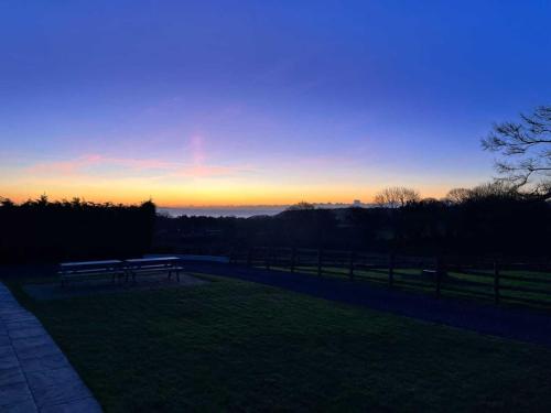 a bench in a field with the sunset in the background at Evening Star Cottages in Saundersfoot