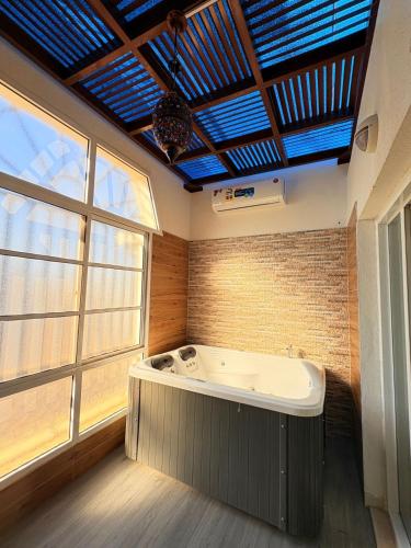 a bath tub in a room with a large window at A'Sinamar Hotel Apartment in Muscat