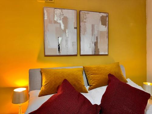 a bedroom with a bed with red and yellow pillows at Hollybush House in Welwyn Garden City