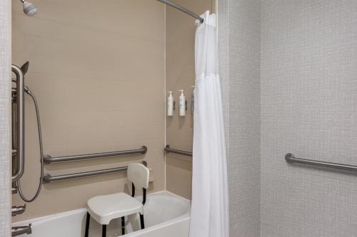 a bathroom with a tub and a toilet and a chair at Hampton Inn Lake Charles in Lake Charles
