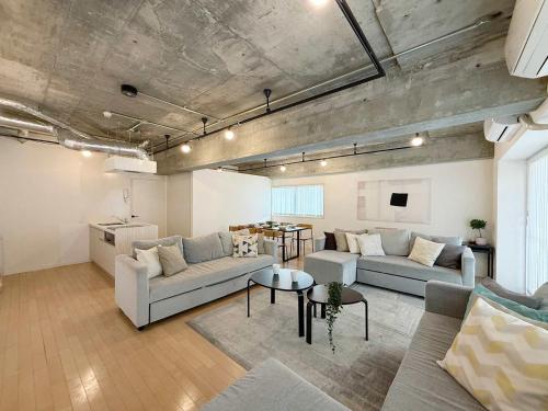a living room with two couches and a table at b hotel M's lea - Beautiful Modern Apt City Center for 10Ppl in Hiroshima