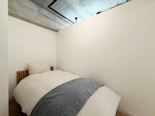 a bedroom with a bed in a white wall at b hotel M's lea - Beautiful Modern Apt City Center for 10Ppl in Hiroshima
