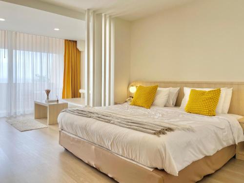 a bedroom with a large bed with yellow pillows at Bangsaen Villa in Bangsaen