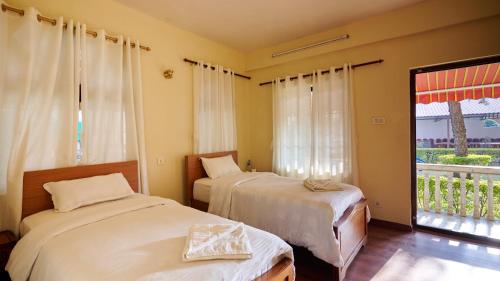 a bedroom with two beds and a window with a view at Hotel Norbu Sangpo in Kathmandu