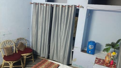 a curtain in a room with two chairs and a table at Prayagraj Sangam Stay Home Kareli Allahabad in Prayagraj
