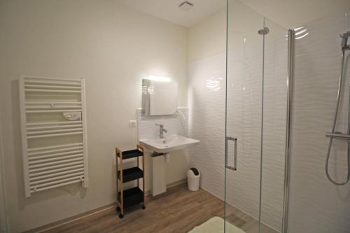 een witte badkamer met een wastafel en een douche bij Gîte Les Champs N°1 in Saint-Mathieu