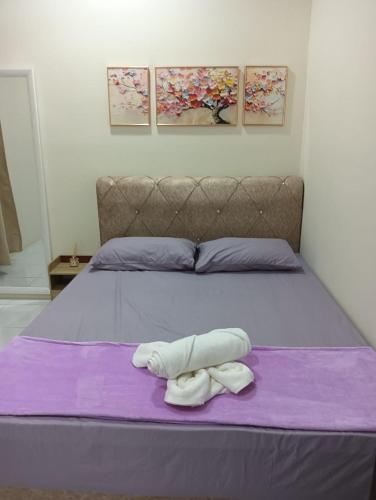 a bed with two towels on a purple blanket at REZEKI MUEZZA 3BR2B Cozy Homestay in Teluk Intan