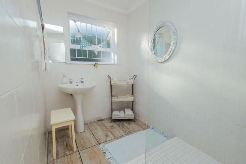 a white bathroom with a sink and a mirror at Seabreeze in Hermanus