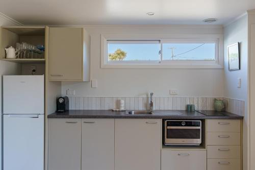 a kitchen with white cabinets and a window at Waimarama Coastal Getaway in Waimarama