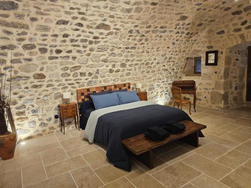 a bedroom with a bed in a stone wall at Commanderie Templière de Cazouls d'Hérault in Cazouls-d Herault