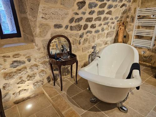 a stone bathroom with a tub and a table at Commanderie Templière de Cazouls d'Hérault in Cazouls-d Herault