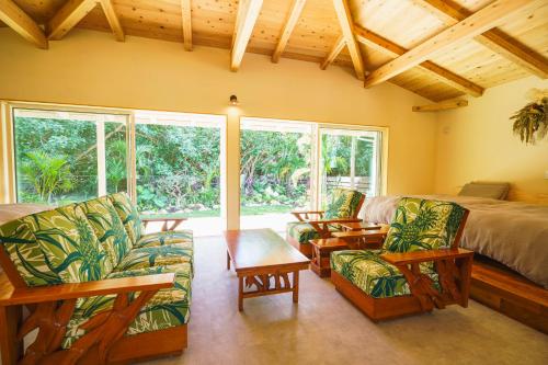 a bedroom with a bed and chairs and a table at Villa UUJI-KAZE ヴィラ ウージ カゼ in Nanjo